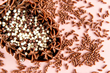 chocolate filled easter egg on pink background with sprinkles, brazilian spoon eggs, easter concept.