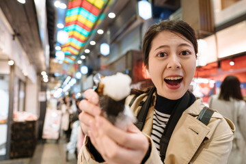 female youtuber in Japan face to camera is showing the inside of sushi rice roll to her fans. asian girl holding japanese traditional food is telling person in front of her open mouth.