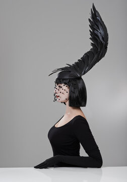 Soaring To New Heights In Fashion. Shot Of A Young Woman In A Wing-shaped Headpiece Sitting In A Studio.