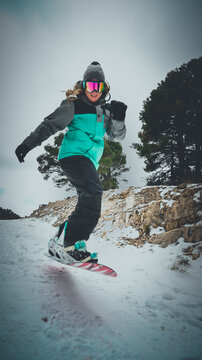 Mujer cauc&aacute;sica rubia de ojos azules esquiando con tabla de Snow en la monta&ntilde;a.