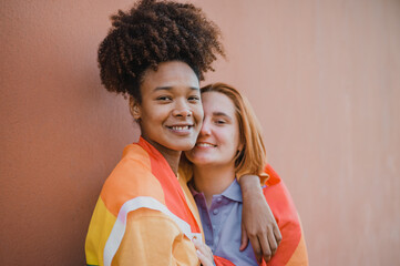 Teen girlfriends hugging near brown wall