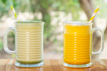 A couple of cups of hot curcuma and matcha latte on wooden floor