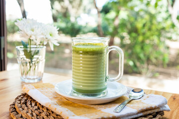 A cup of hot matcha latte on wooden floor