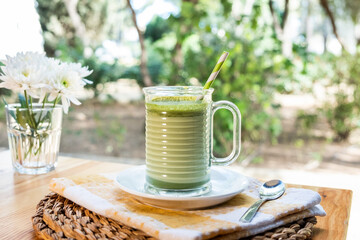 A cup of hot matcha tea latte on wooden floor. Latte tea matcha with a metalic spoon on wooden...