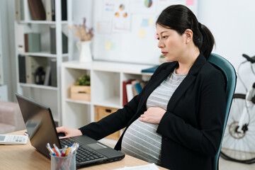 tired overworked pregnant woman at workplace in bright modern office. exhausted maternity lady...
