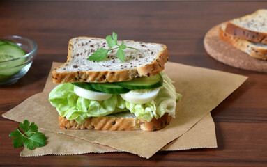 Sandwich with egg, cucumber and salad on craft paper
