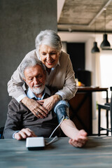 Happy senior couple measuring blood pressure at home