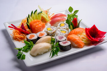Japanese food mix including sushi and sashimi on white plate.