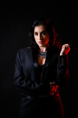 Portrait of a young beautiful woman with dark hair of European appearance. Dressed in a black jacket. Isolated on black background