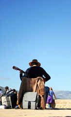 Street musician playing the spanish guitar with a blue sky background
