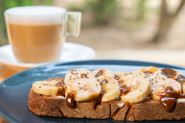 Coffee with milk and banana and caramel sandwich. Vegan breakfast in a bar.