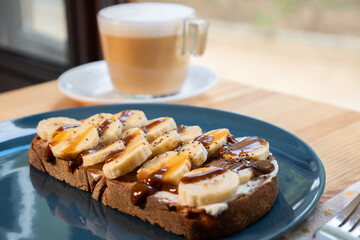 Coffee with milk and banana and caramel sandwich. Vegan breakfast in a bar.