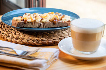 Coffee with milk and banana and caramel sandwich. Vegan breakfast in a bar.