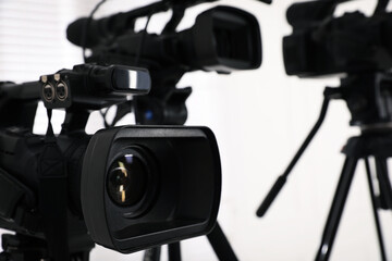 Modern video camera indoors, focus on lens. Professional media equipment for broadcasting event