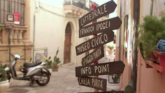 Pointers of the movement of tourists in the city. The inscriptions orient people in the old area. In the background is a scooter in bokeh.
