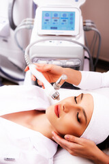 Clinic of aesthetic cosmetology. Facial exfoliation procedure. The patient does a hydro-peeling at the cosmetologist. Facial skin rejuvenation concept.