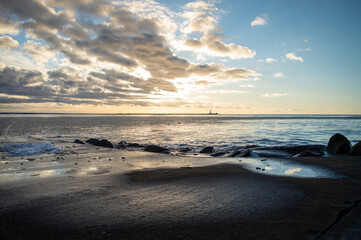 Sunset view from a pier. Cold climate mouth of the river at sunset. Distant lighthouse on horizon
