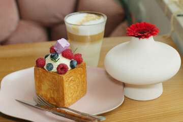 cube formed dessert with cream, raspberry, blueberry and marshmallow topping with coffee latte and flower close up photo