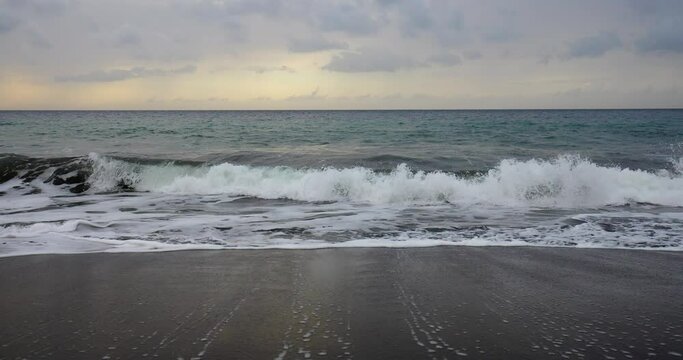 Black sand beach wave coming in during sunset at Playa de Valle Gran Rey in slow motion