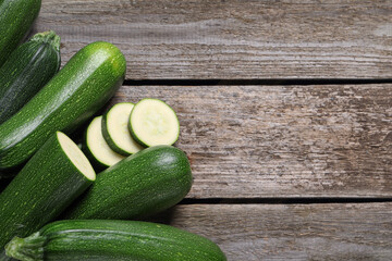 Whole and cut ripe zucchinis on wooden table, flat lay. Space for text