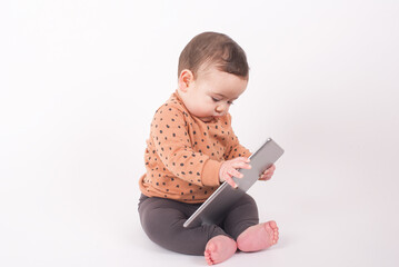Adorable baby boy wearing animal print sweater sitting on white background holding a tablet pad and...