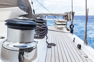 Fototapeta premium Part of the teak deck of a sailing yacht with bollards and sail winches for fixing the sail ropes.