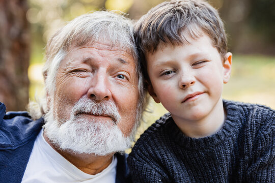 Positive senior man and little child looking at camera