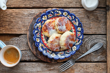 Cottage cheese pancakes with condensed milk. Side view, wooden background. Syrnik