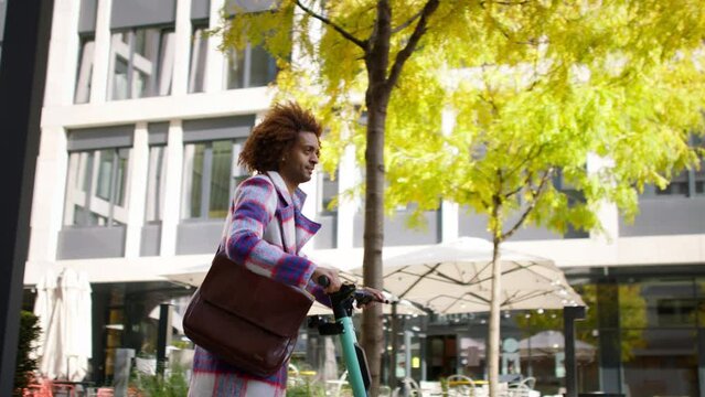 Cool multiracial mid audlt man riding electric scooter in street