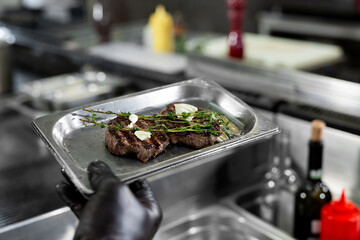 Meat steak with garlic and thyme on a baking sheet in the hands of the cook is ready for baking.