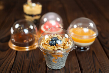 Variety of desserts in cups, including chia pudding on a brown wooden background.