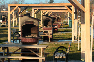 Wooden arbors with tables benches and barbeque equipment in a public park