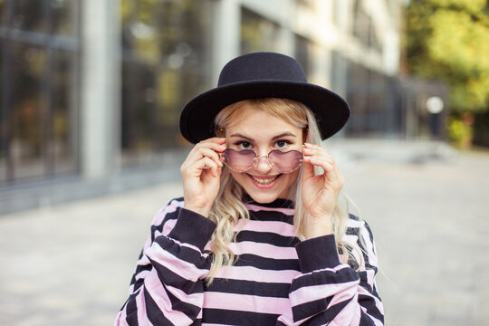 Portrait of smiling charismatic hipster girl in glasses and hat outdoors
