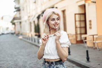 Fototapeta premium Portrait of a charming young woman in a beret and glasses on European street