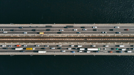 Aerial top view of cars and subway passing the bridge over the river in the city