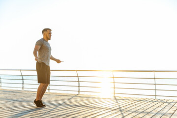 Athletic man jumping rope in the early morning on beach