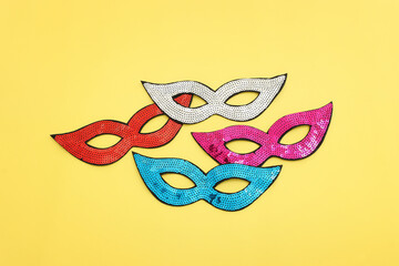 Holidays image of carnival party sequins masks over yellow background. view from above