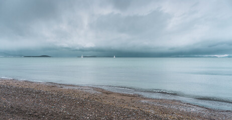 Seascape with cloudy day and sailing boats on horizon