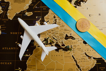 The plane and the Ukrainian flag on the background of the map with bitcoin