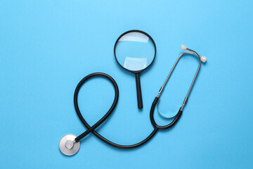 Stethoscope with a magnifying glass on a blue background. Diagnosis of diseases. Top view