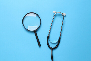 Stethoscope with a magnifying glass on a blue background. Diagnosis of diseases. Top view
