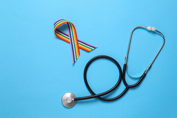 Stethoscope with rainbow lgbt ribbon on blue background. Top view