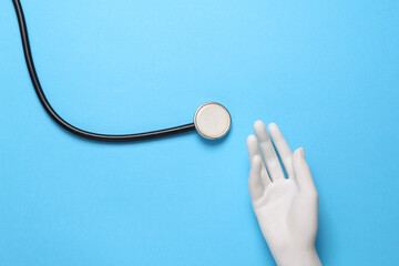 Plastic hand and stethoscope on blue background. Medicine concept