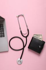 Wallet with money, laptop and stethoscope on pink background. Business concept