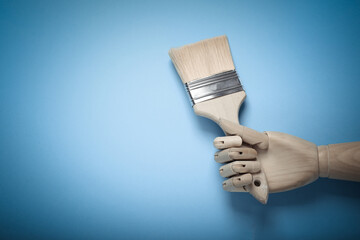 Wooden hand holding Paint brush on blue background