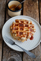 Waffles with caramel sauce. Wooden background. Top view. 