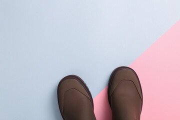 Rubber fashion boots on pink blue background. Top view