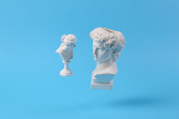 Levitating Antique Plaster busts of David and Venus on blue background with shadow. Conceptual pop....