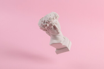 Levitating Antique Plaster David bust on pink background. Conceptual pop. Minimal still life...