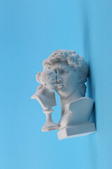 Antique Plaster busts of David and Venus on blue background. Conceptual pop. Minimal still life photography